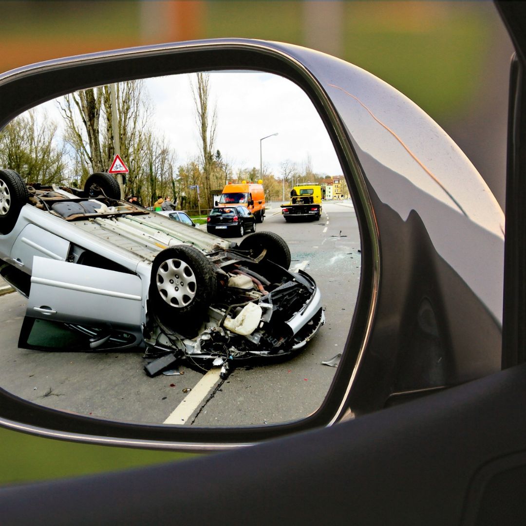 flipped car on the road visible in side mirror