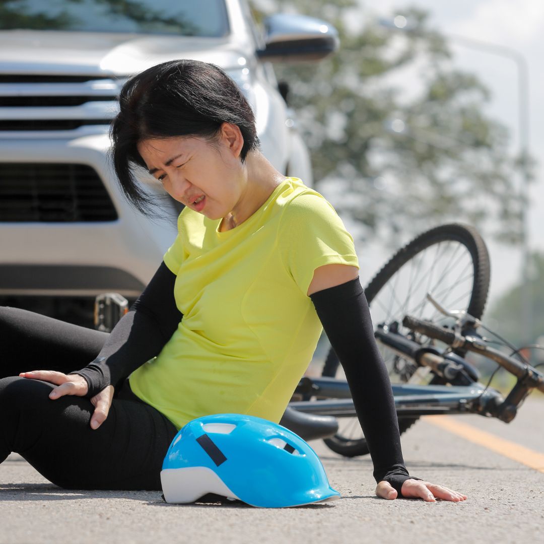 cyclist holds legs after accident with car