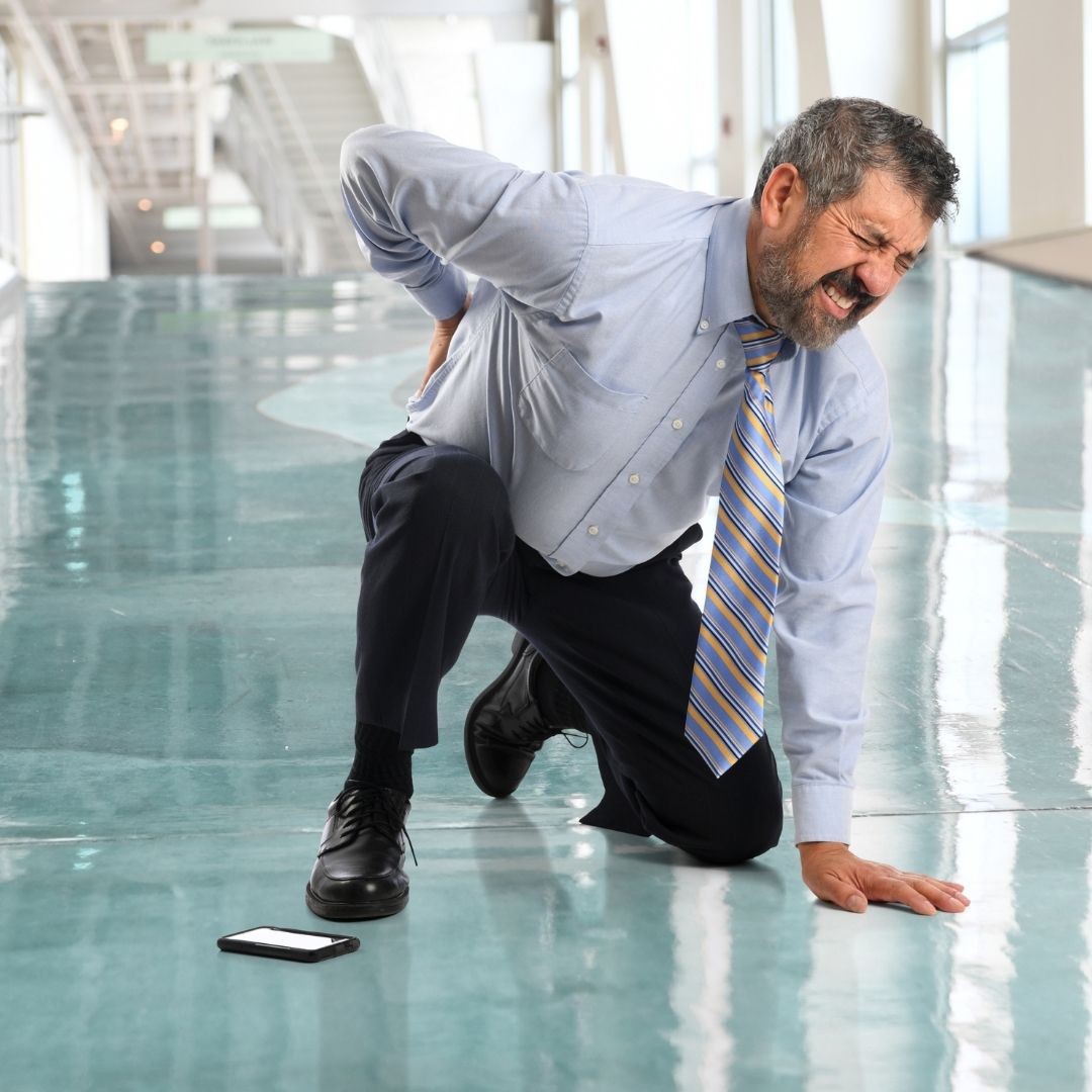 a man clutching his back after falling on a commercial floor